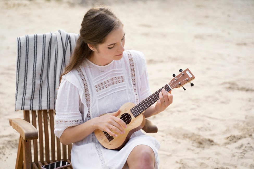 a young woman in a white folk dress playing the ukulele
