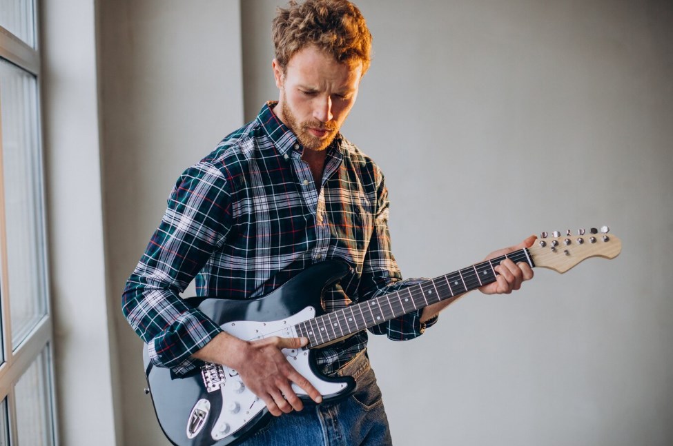 a man in a plaid shirt holding an electric guitar