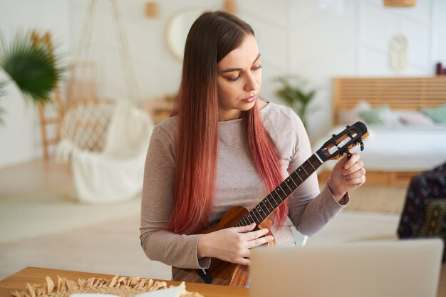Woman tuning ukulele for practice