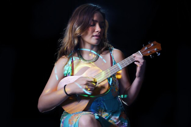Girl playing the ukulele on a black background