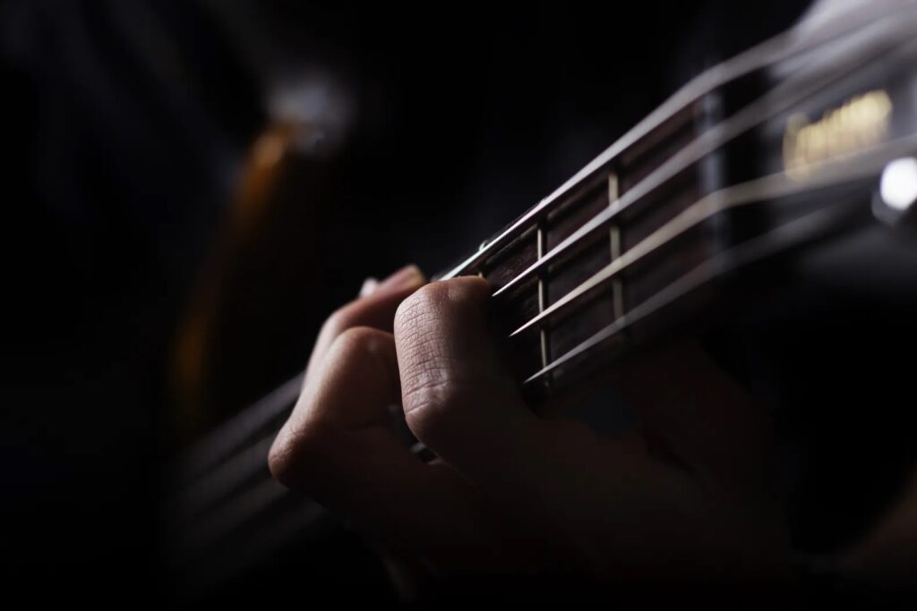 Fingers on the strings of a guitar, close-up view