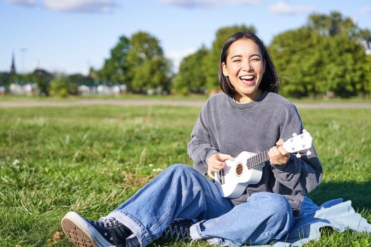 Woman Smiling and Playing Ukulele Sitting in Park
