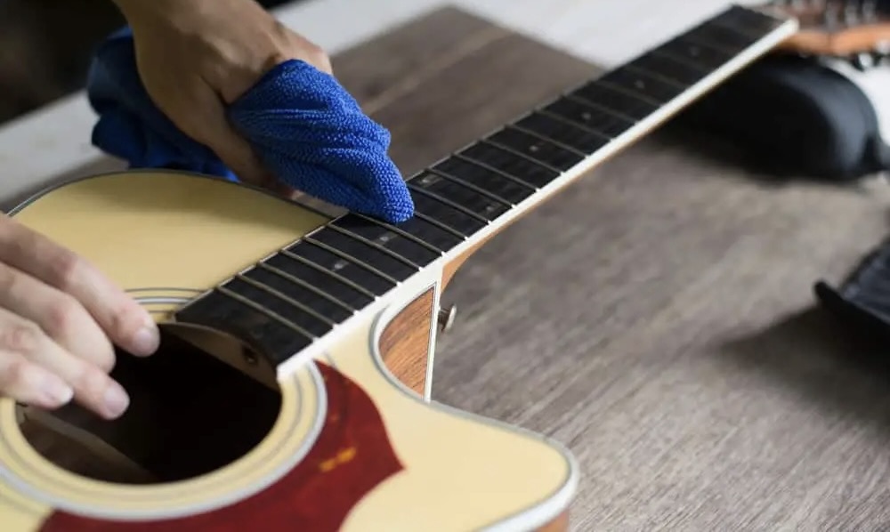 Hand cleaning guitar neck with towel