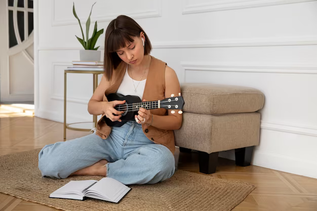 Girl sitting on the floor plays the ukulele