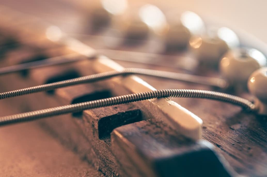 Close-up of guitar strings and bridge on a wooden fretboard with a vintage tone