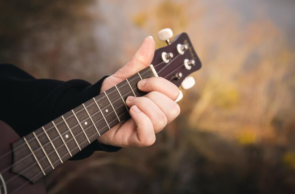 a hand forming a chord on a ukulele's fretboard