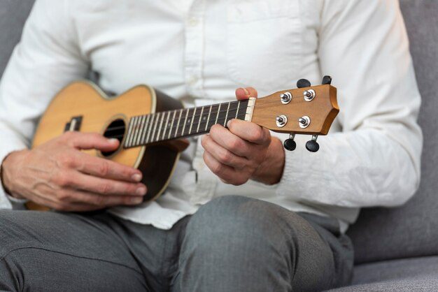 Man playing ukulele while sitting on sofa